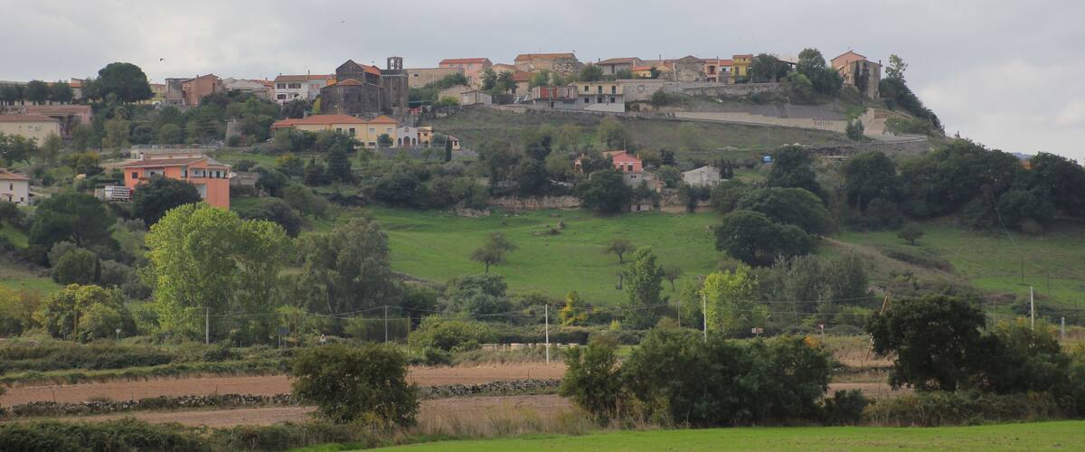 A hillside village with buildings and greenery.