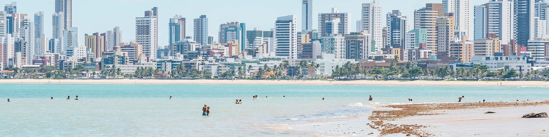A coastal cityscape with a beach and high-rise buildings.