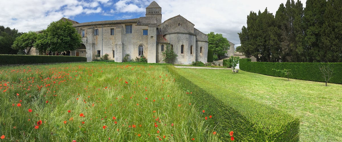 A historic building with a tower, surrounded by a well-maintained garden with red poppies.