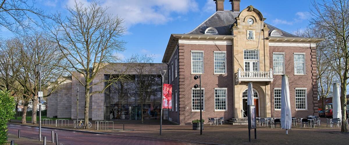 A historic building with a prominent clock tower, large windows, and a brick facade.