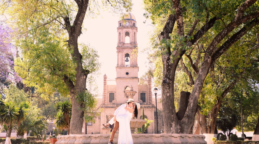 A couple having a romantic kiss in front of the San Miguel parish church in Temascalcingo, a Mexican village among the trees