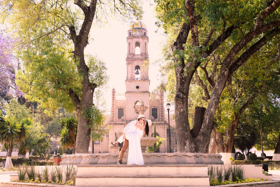 A couple having a romantic kiss in front of the San Miguel parish church in Temascalcingo, a Mexican village among the trees