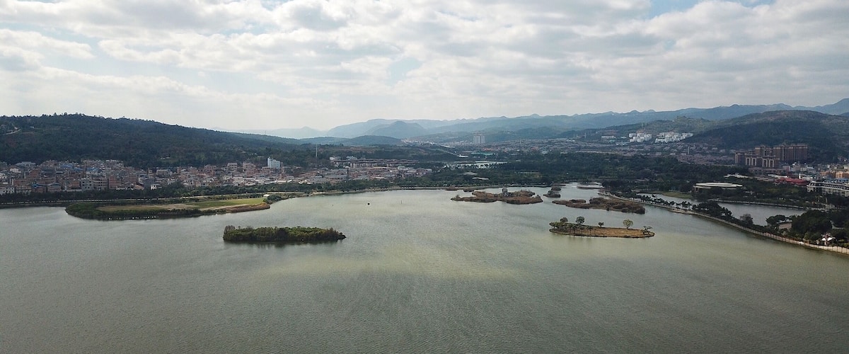 A large body of water with several islands, surrounded by a cityscape and distant mountains.