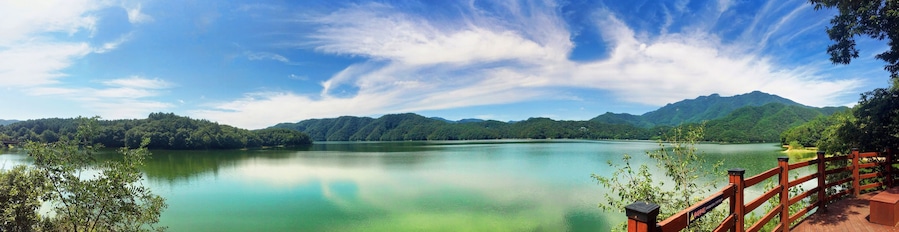 Un lago tranquilo rodeado de montañas verdes y un cielo azul despejado.
