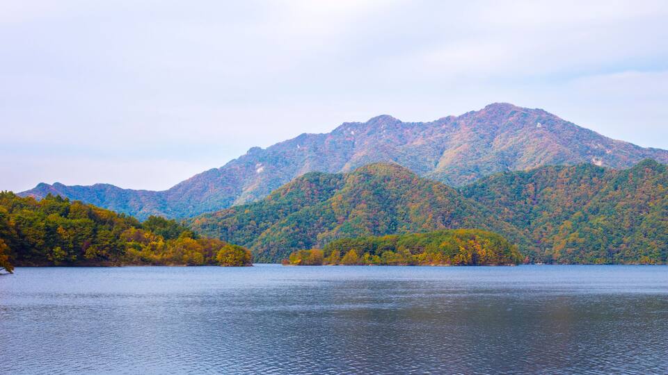 A mountain range with autumn foliage and a calm lake.