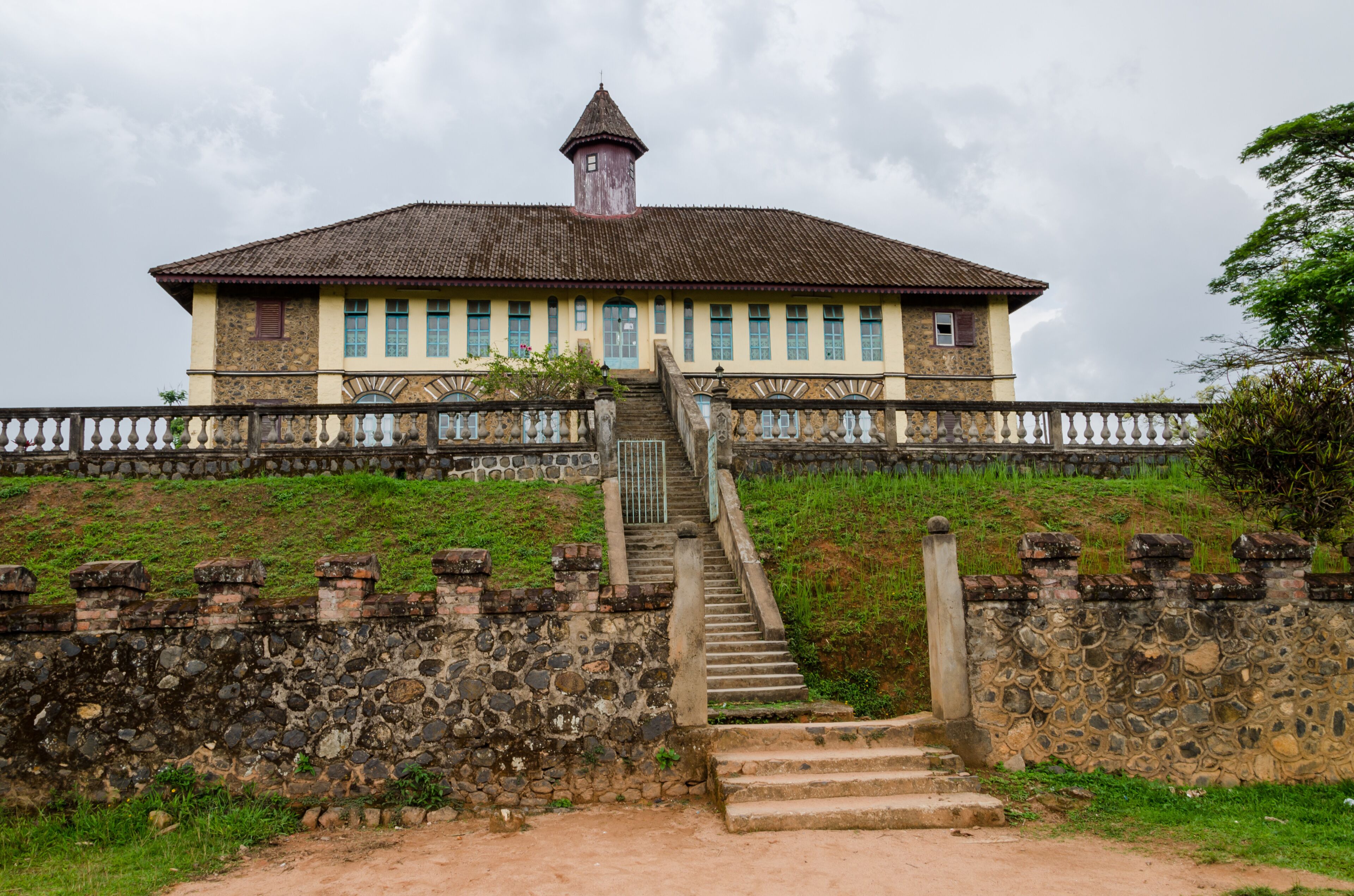A historic building with a tower, stone steps, and a stone wall.
