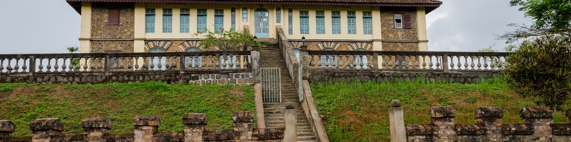 A historic building with a tower, stone steps, and a stone wall.