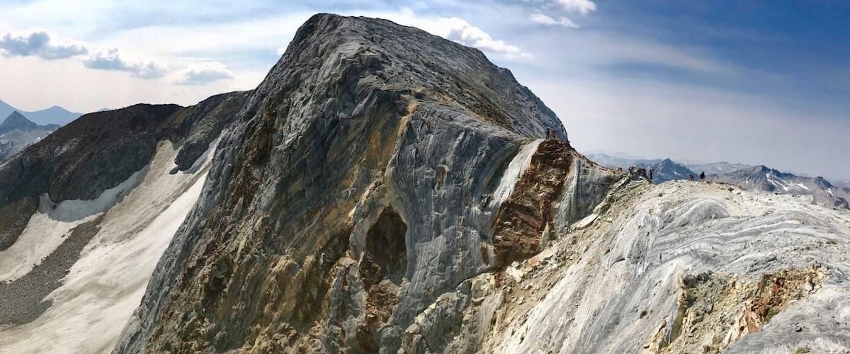 A rugged mountain peak with a prominent overhang and a deep crevice.