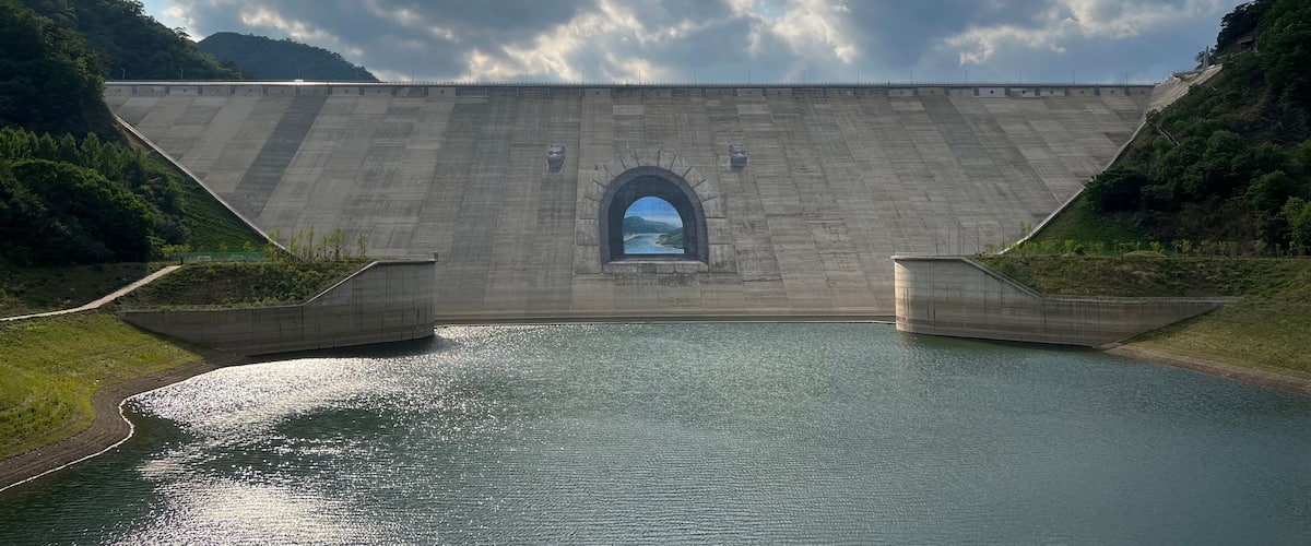 A large dam with a scenic view through an arched opening.