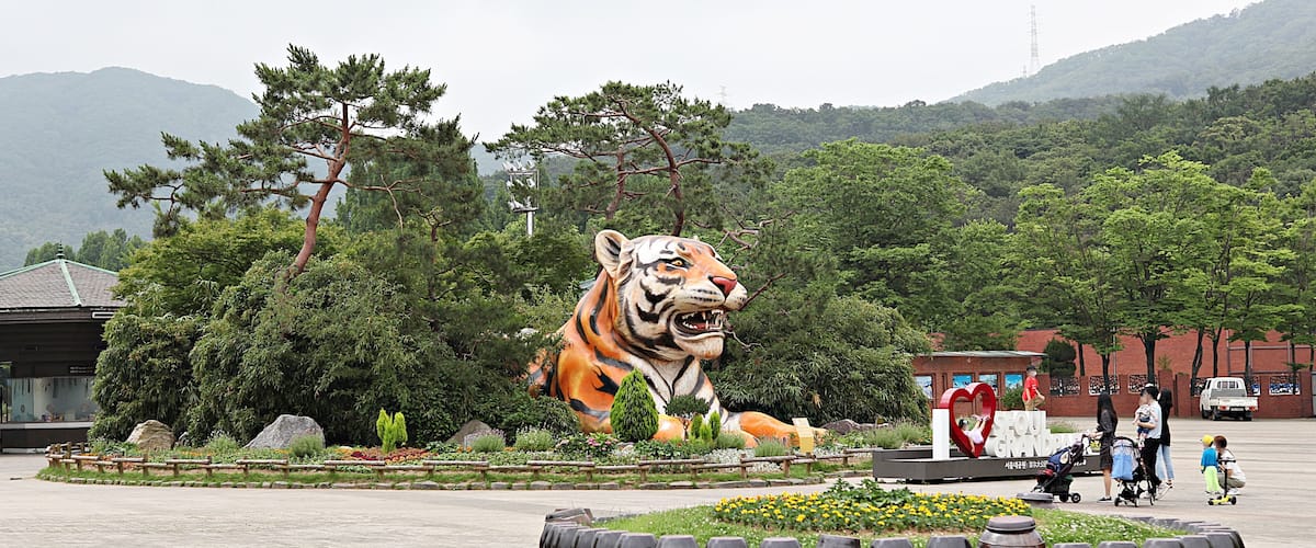 A large tiger statue surrounded by greenery and trees.