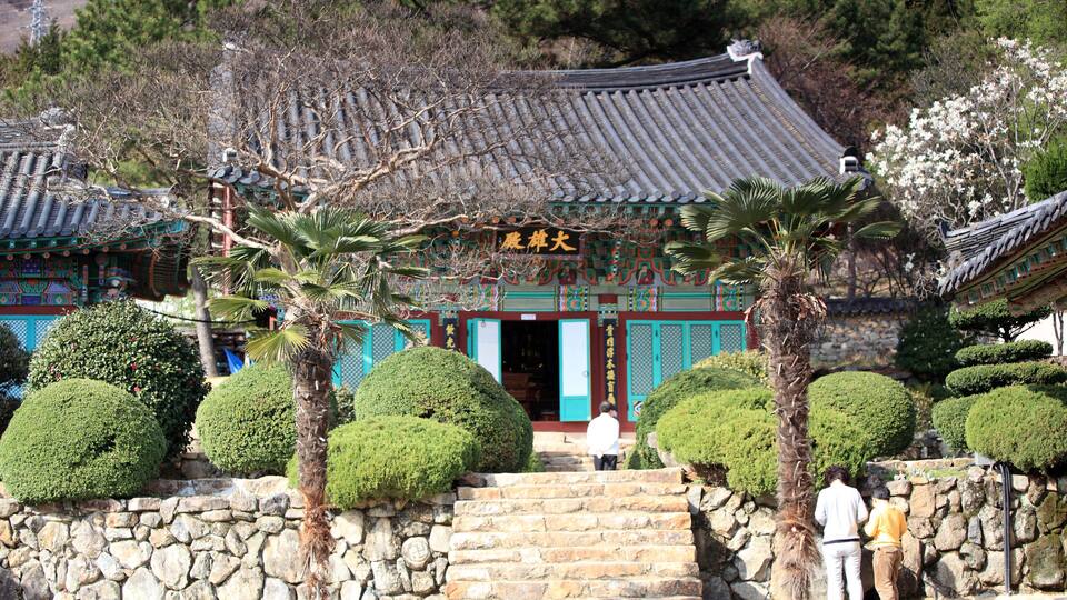 A traditional Korean temple with ornate architecture, stone steps, and well-maintained gardens.