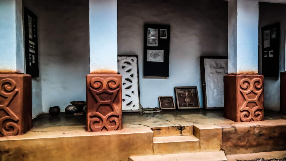 A porch with decorative pillars, a door, and framed artwork on the wall.