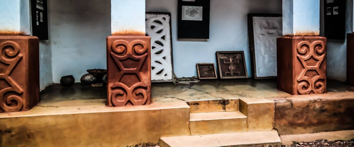 A porch with decorative pillars, a door, and framed artwork on the wall.