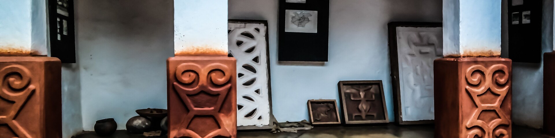 A porch with decorative pillars, a door, and framed artwork on the wall.