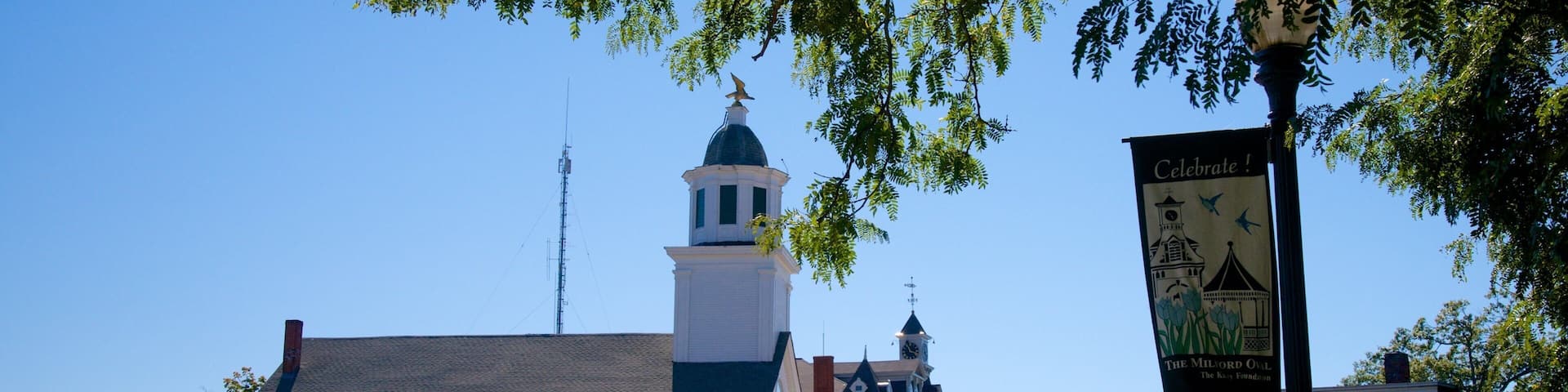A historic downtown street with buildings, a church steeple, and a banner.