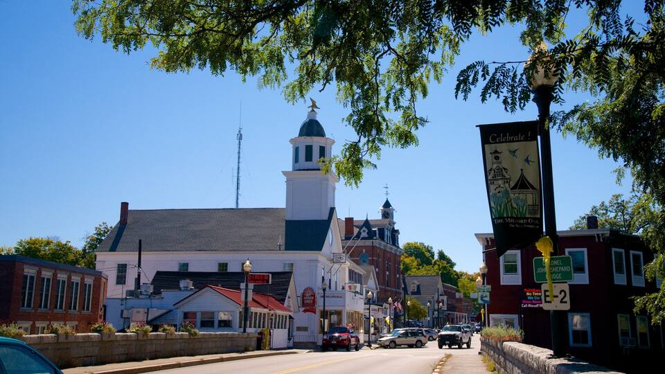 A historic downtown street with buildings, a church steeple, and a banner.