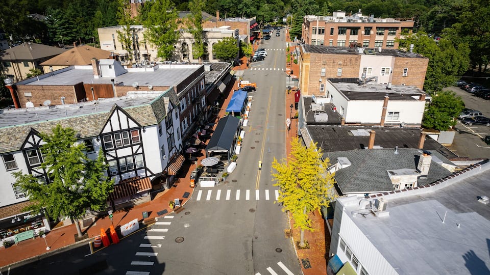 A town square with a crosswalk, buildings, and a tree with yellow leaves.