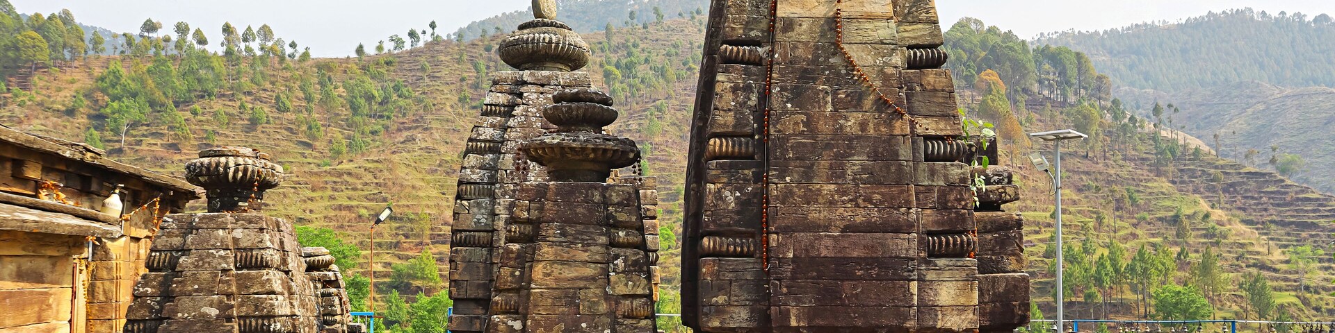Ancient stone structures with intricate carvings, set against a backdrop of lush green hills.