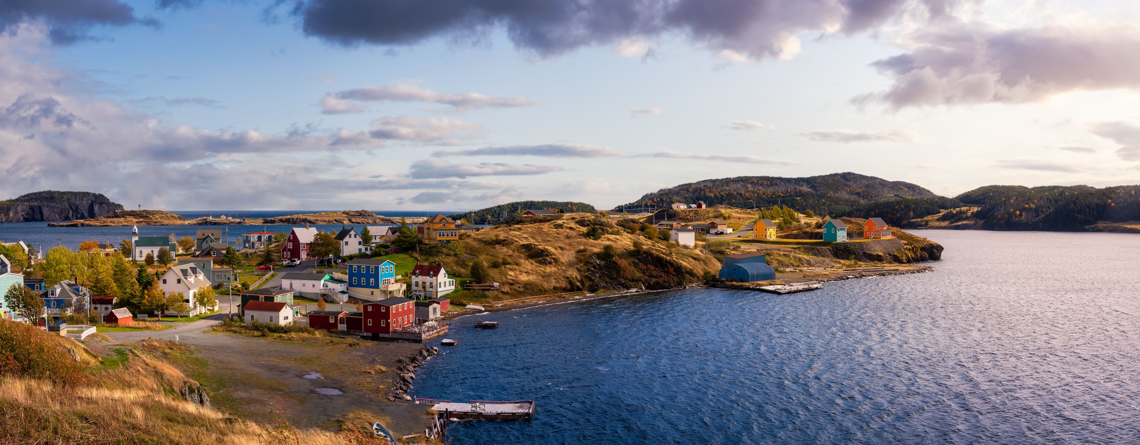 Panoramic view of a small town on the Atlantic Ocean Coast. Dramatic Colorful Sunrise Sky Art Render. Taken in Trinity, Newfoundland and Labrador, Canada.