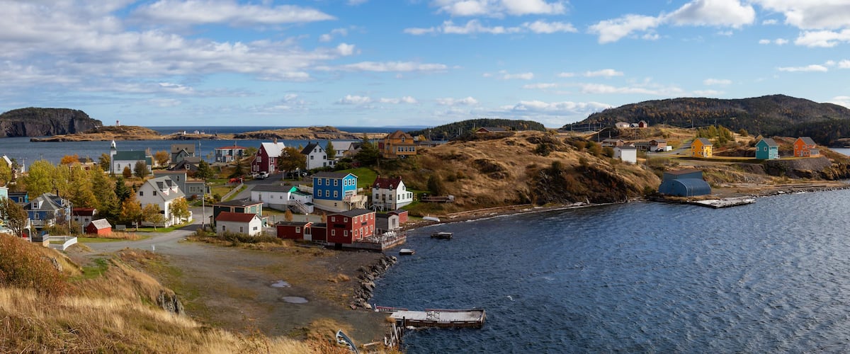 A coastal village with colorful houses, a lighthouse, and a rugged coastline.