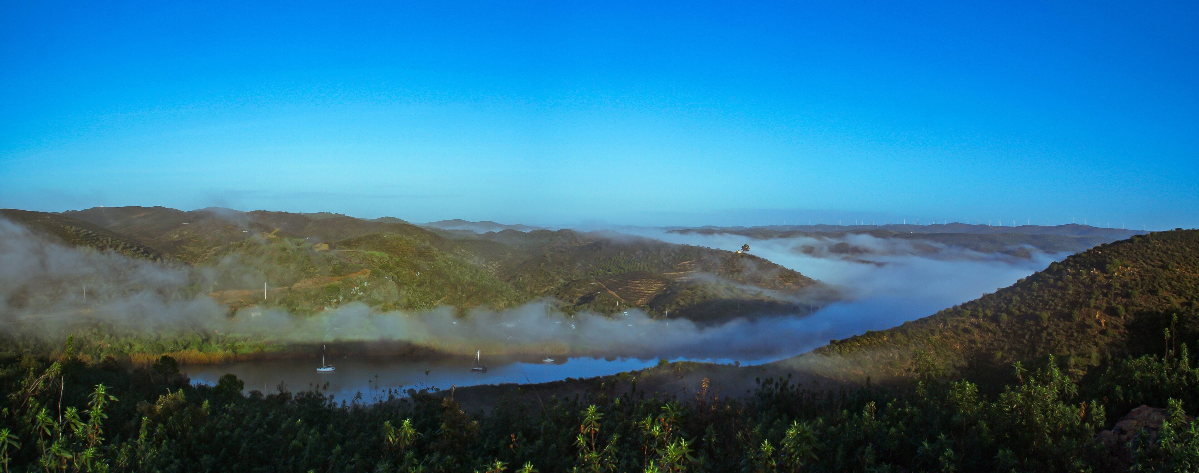 Panorámica de la frontera entre España y Portugal en el sur de la Península Ibérica. El brumoso río Guadiana al amanecer en Sanlúcar de Guadiana y Alcoutim (Pequeños pueblos de España y Portugal).