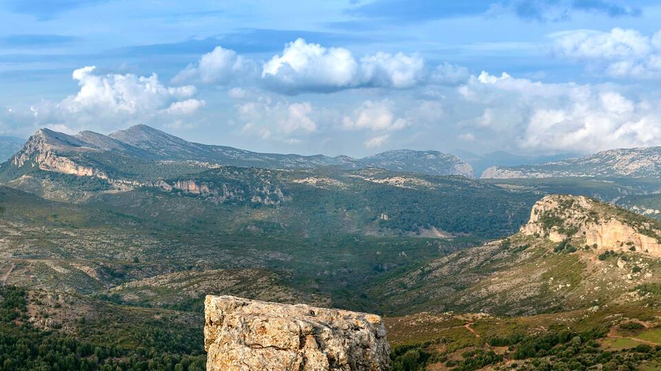 A mountainous landscape with rocky outcrops and dense forests.