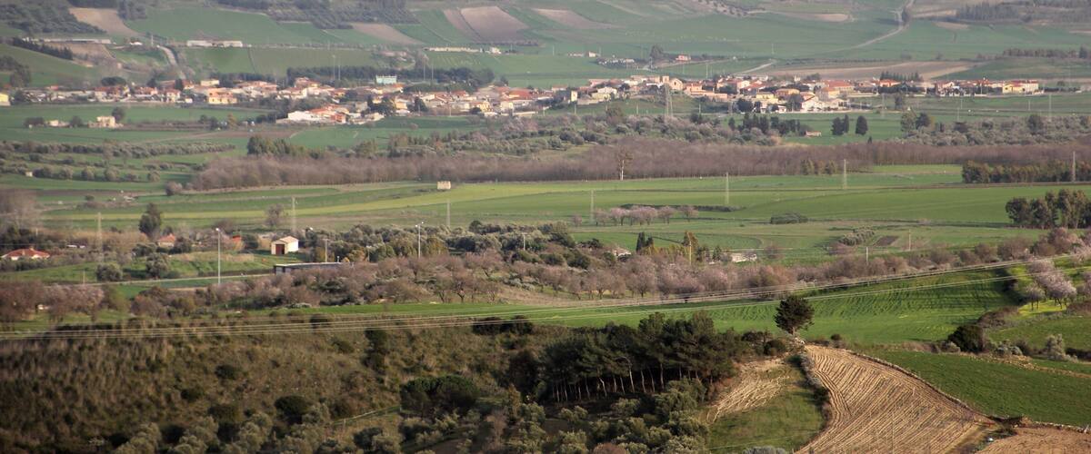 A rural landscape with rolling hills, fields, and scattered buildings.