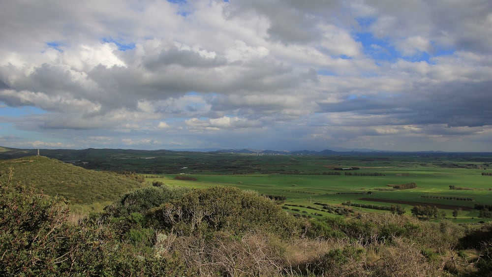 Un paysage vallonné, avec de douces collines verdoyantes et un ciel nuageux.