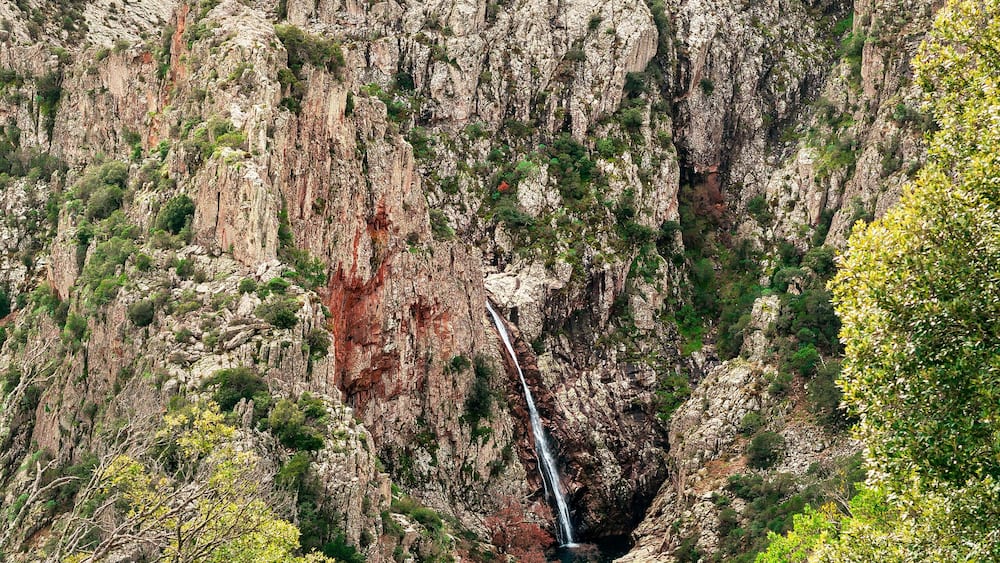 Un canyon escarpé, avec une cascade et une végétation luxuriante.