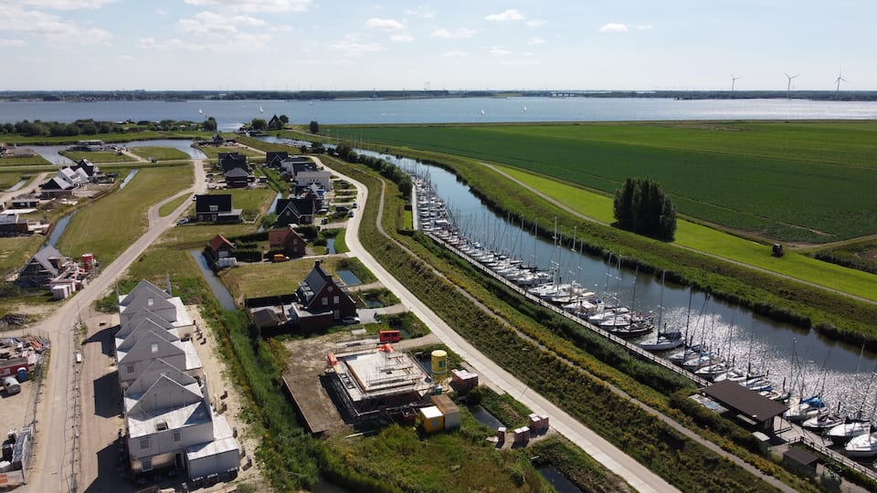 A canal with boats, a river, and green fields.