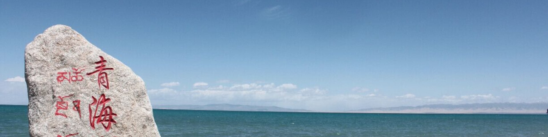 Double language milestone (Chinese and Tibetan). Qinghai Lake is easy to reach by bus from Xining