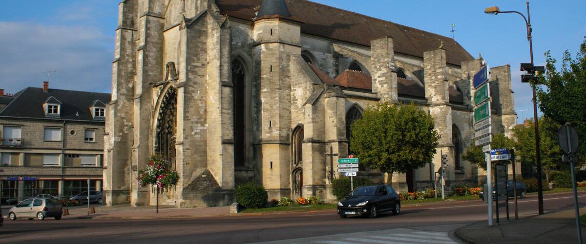 A historic church with a large dome and multiple spires, surrounded by modern buildings and a clear sky.