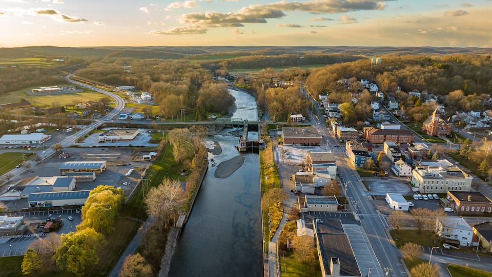 An aerial view of a town with a river, roads, and buildings.