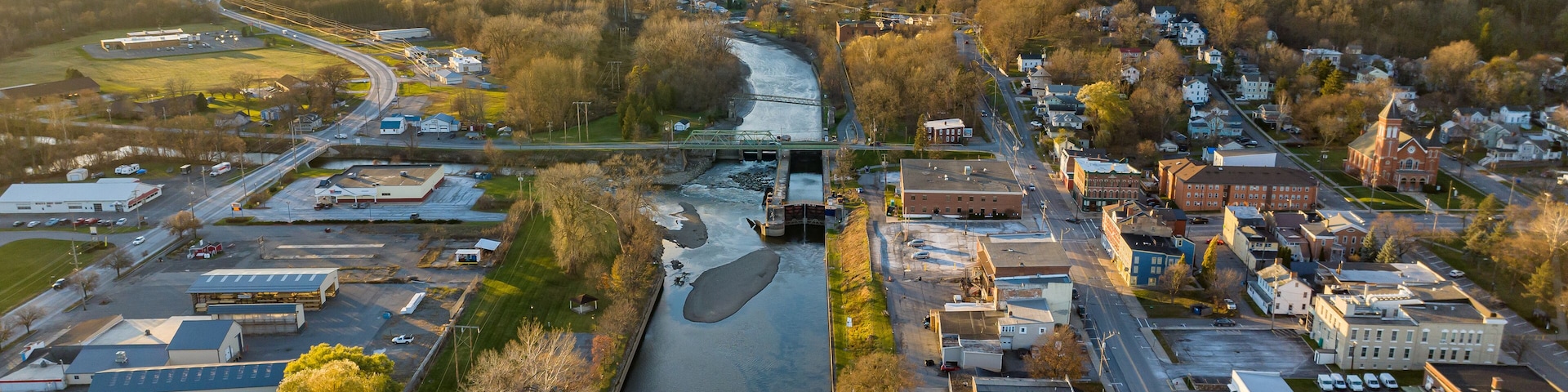An aerial view of a town with a river, roads, and buildings.