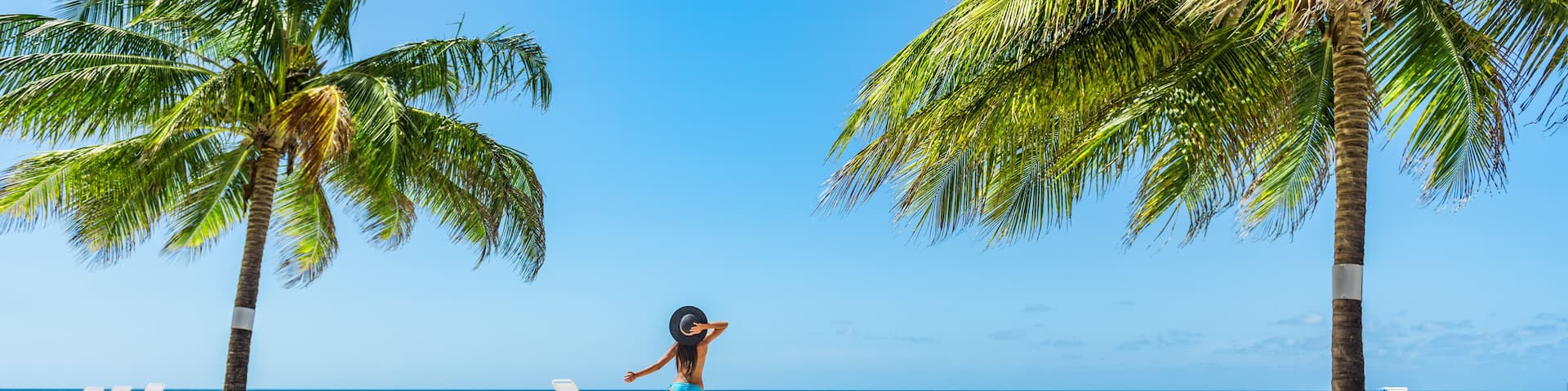 Caribbean tropical beach vacation woman dancing of happiness under the sun. Summer holidays travel getaway banner panorama.