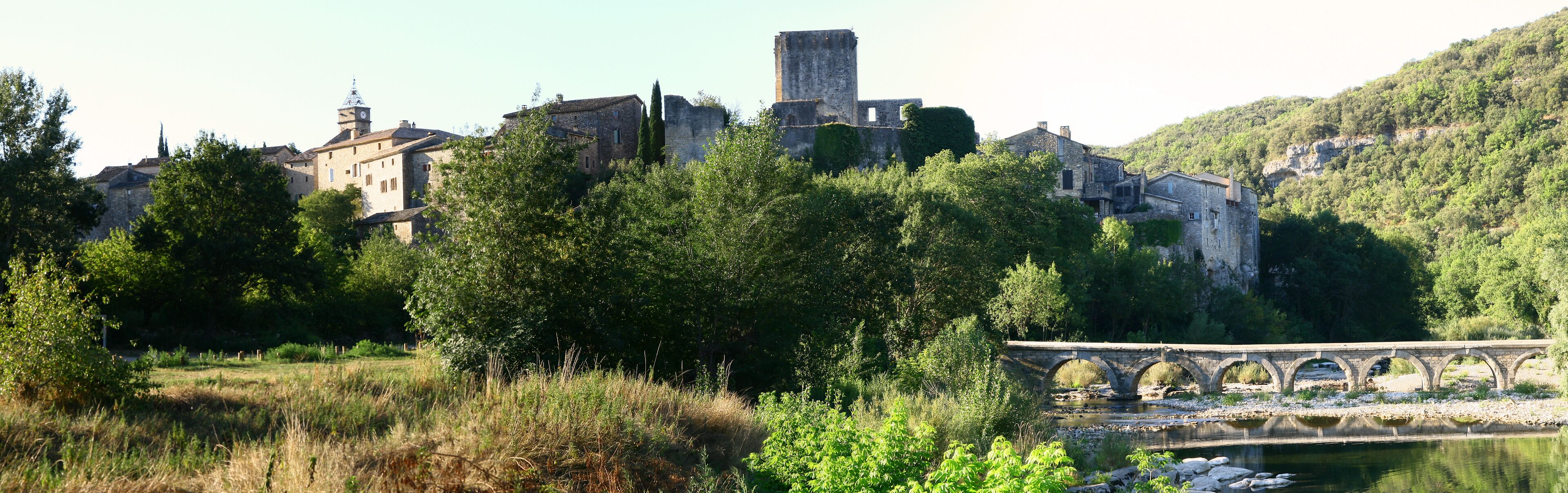 A historic town with medieval architecture, a river, and a stone bridge.