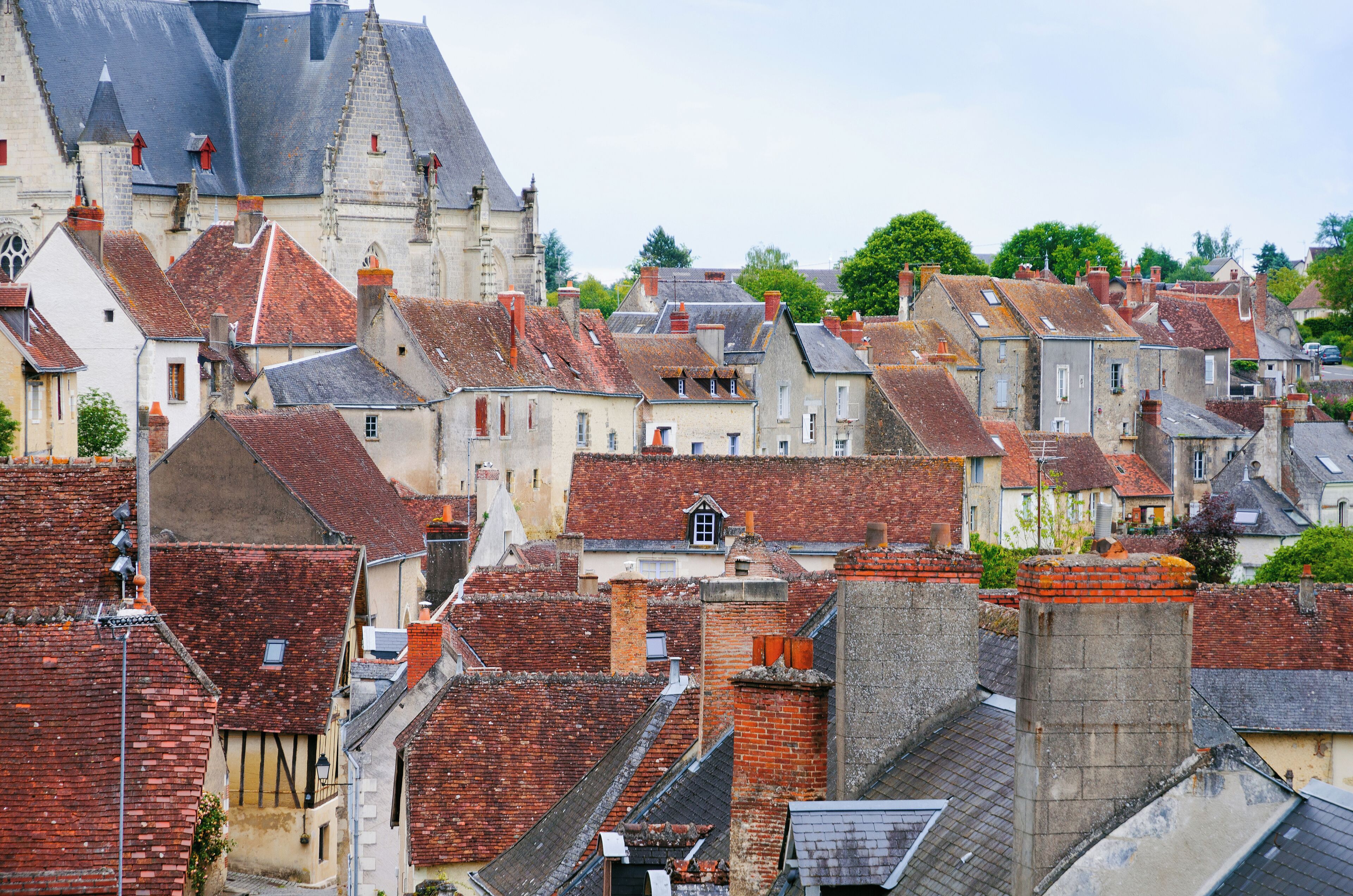 A historic town with red-tiled roofs, medieval architecture, and a prominent church with a steeply pitched roof.