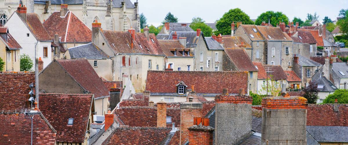 A historic town with red-tiled roofs, medieval architecture, and a prominent church with a steeply pitched roof.