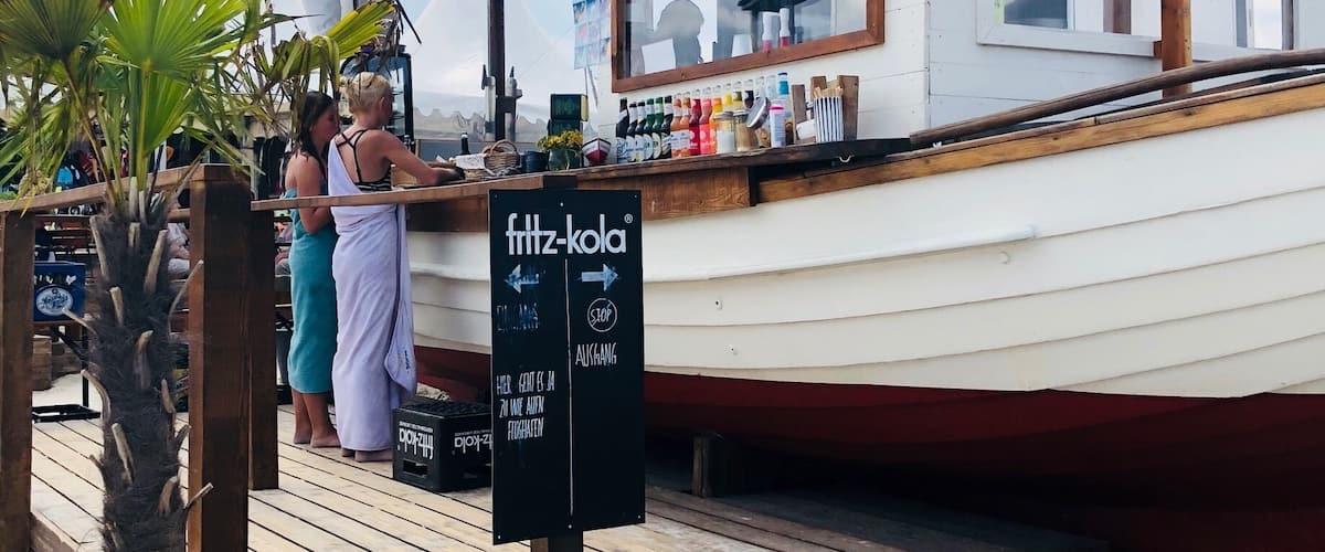 A wooden dock with a sign for 'fritz-kola' and a boat in the background.