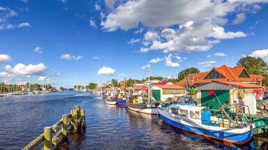 A harbor with boats, a wooden pier, and buildings with red roofs.