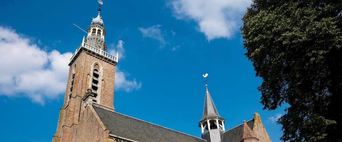 A historic church with a prominent tower and spire, set against a clear blue sky.