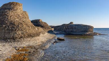 A rocky coastline with layered cliffs and calm sea.