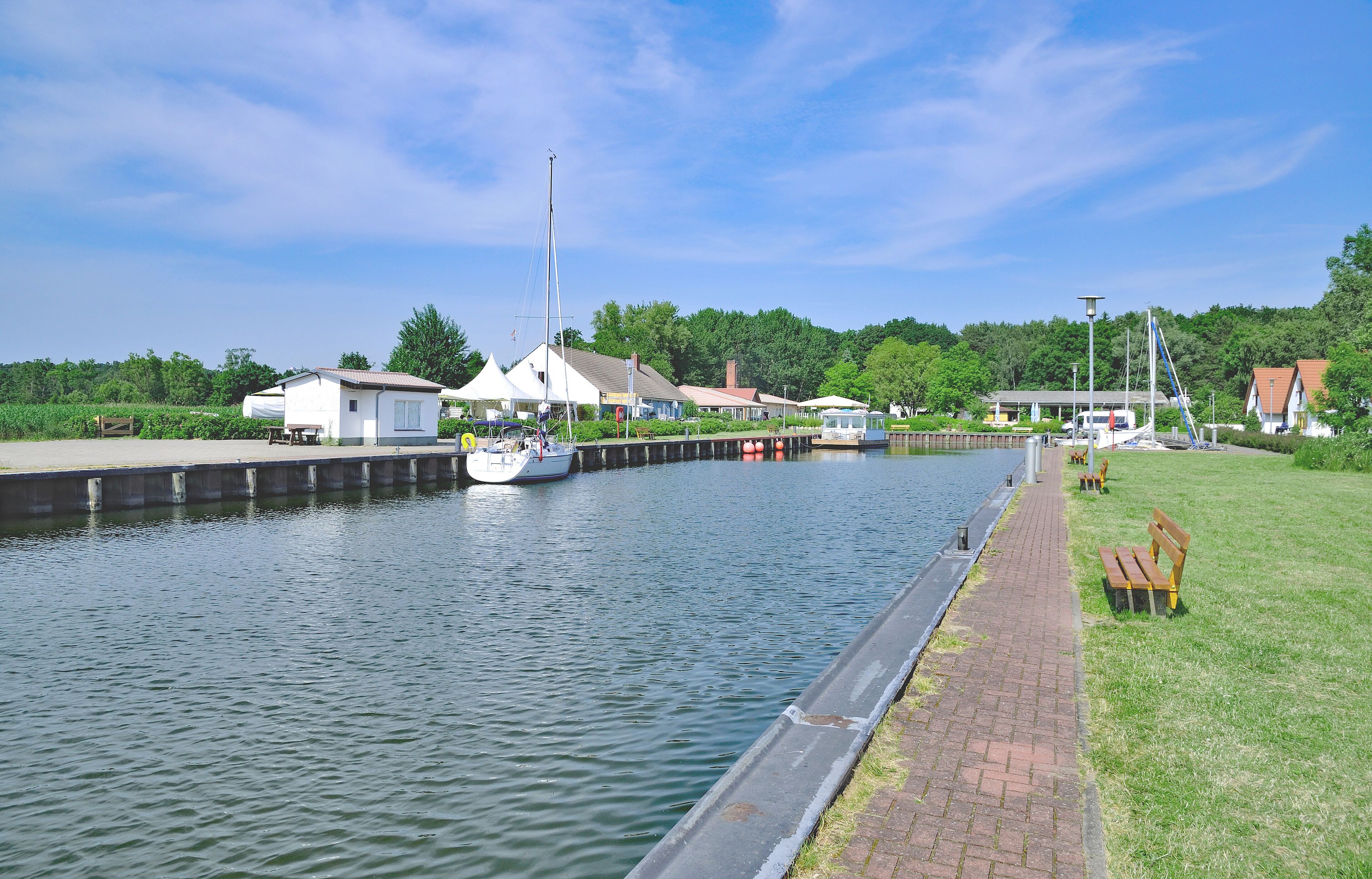 A canal with a boat, a dock, and buildings along the water.