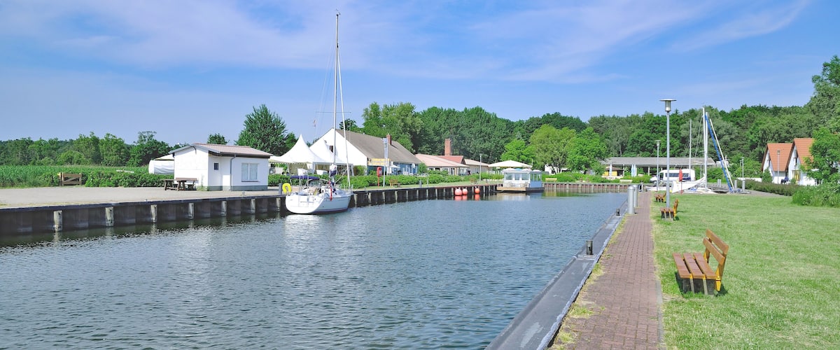 A canal with a boat, a dock, and buildings along the water.