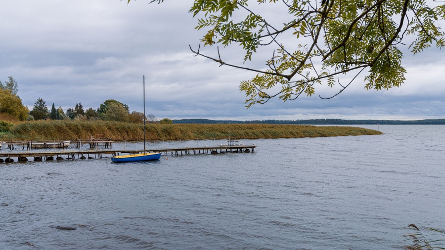 A wooden pier with a boat and some benches on the coast of the Krumminer Wiek in Neeberg, Mecklenburg-Western Pomerania, Germany