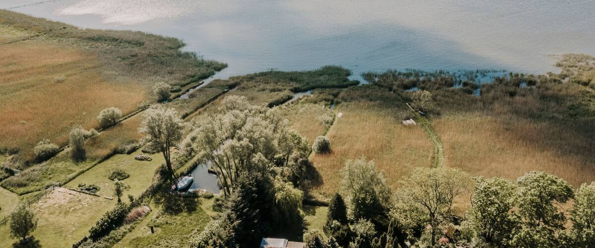A coastal landscape with a large body of water, a small settlement with houses, and a distant shoreline.