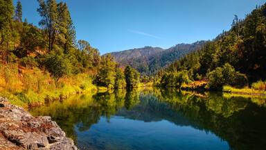 Autumn foliage and tranquil water reflections over the rocky creek on Trinity River near Del Loma, Northern California