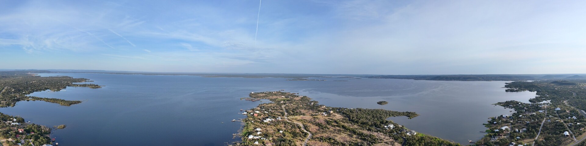 Un paysage côtier caractérisé par une vaste étendue d’eau, plusieurs petites îles et des maisons dispersées le long du littoral.
