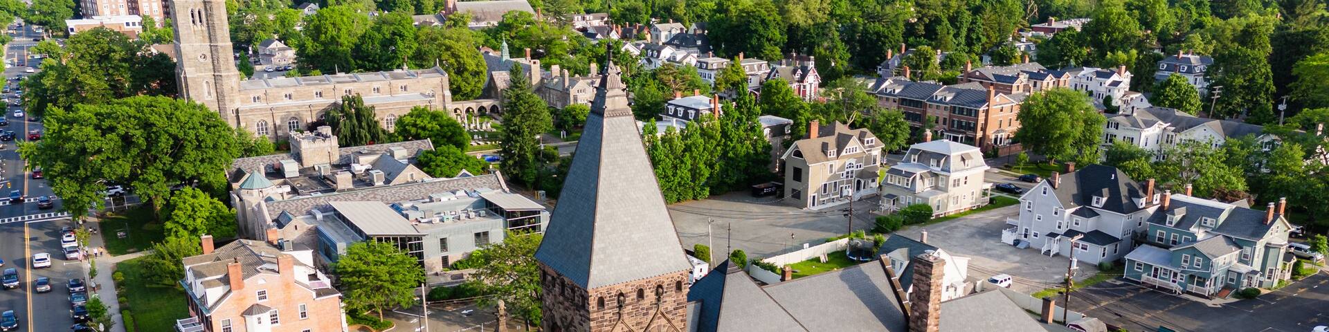 A town with a prominent church tower, surrounded by residential houses and lush greenery.