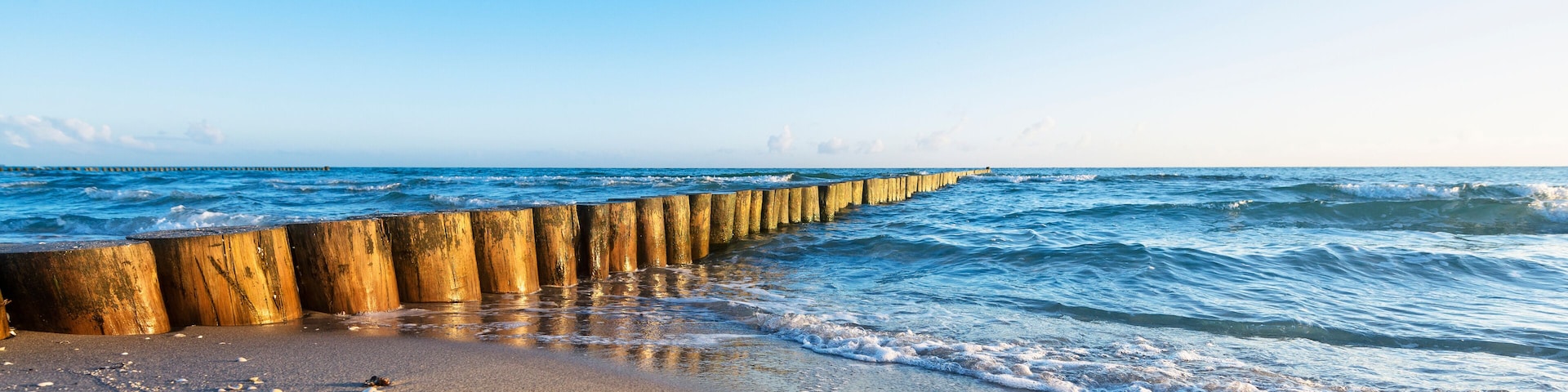 Eine Holzkonstruktion zum Schutz vor dem Meer entlang eines Strandes, wo Wellen auf die KĂŒste branden.
